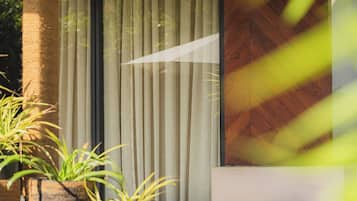 A modern outdoor area with a concrete bench, a vertical garden, and a large window with vertical blinds.