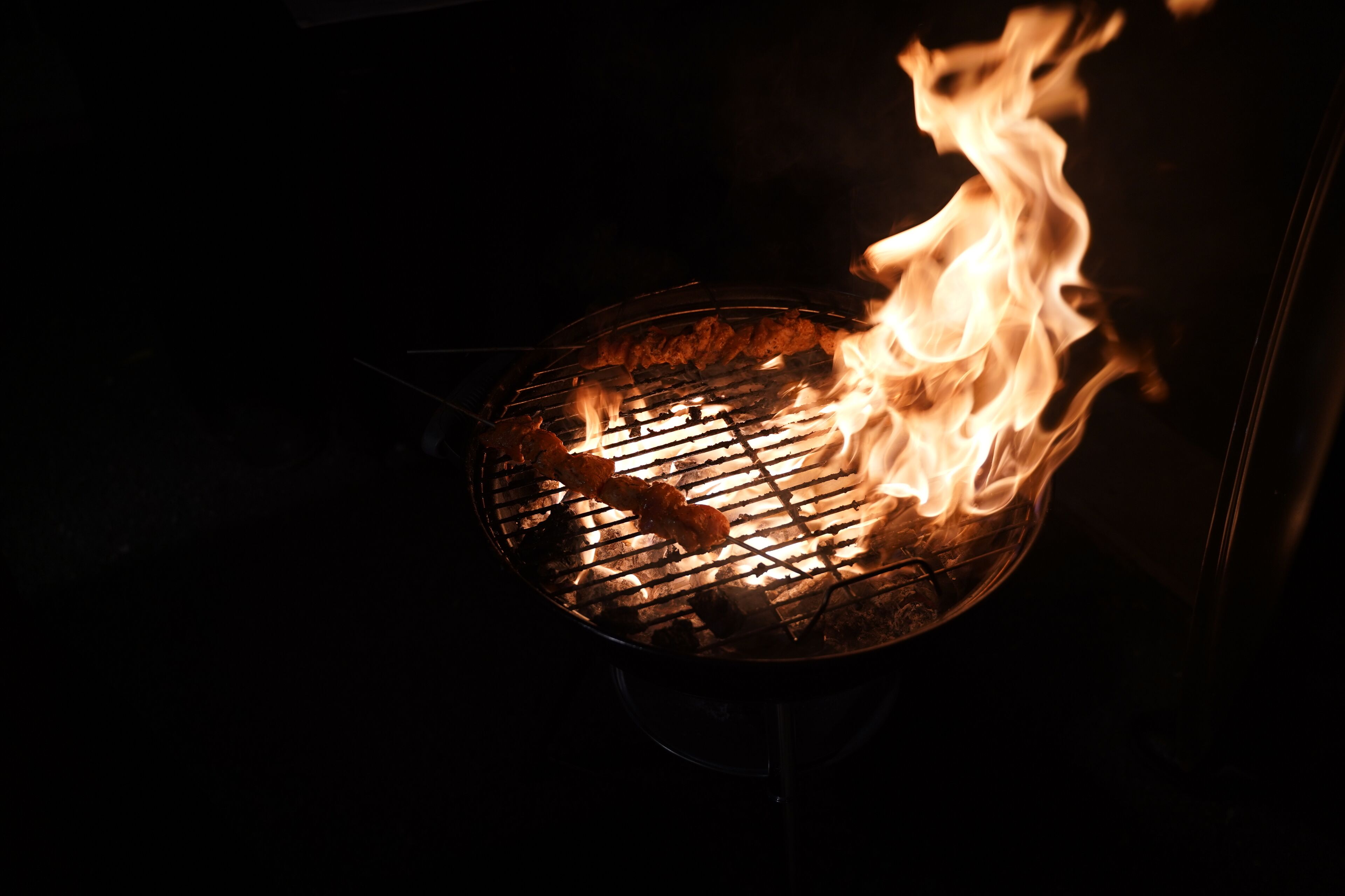 A grill with visible flames and food being cooked.
