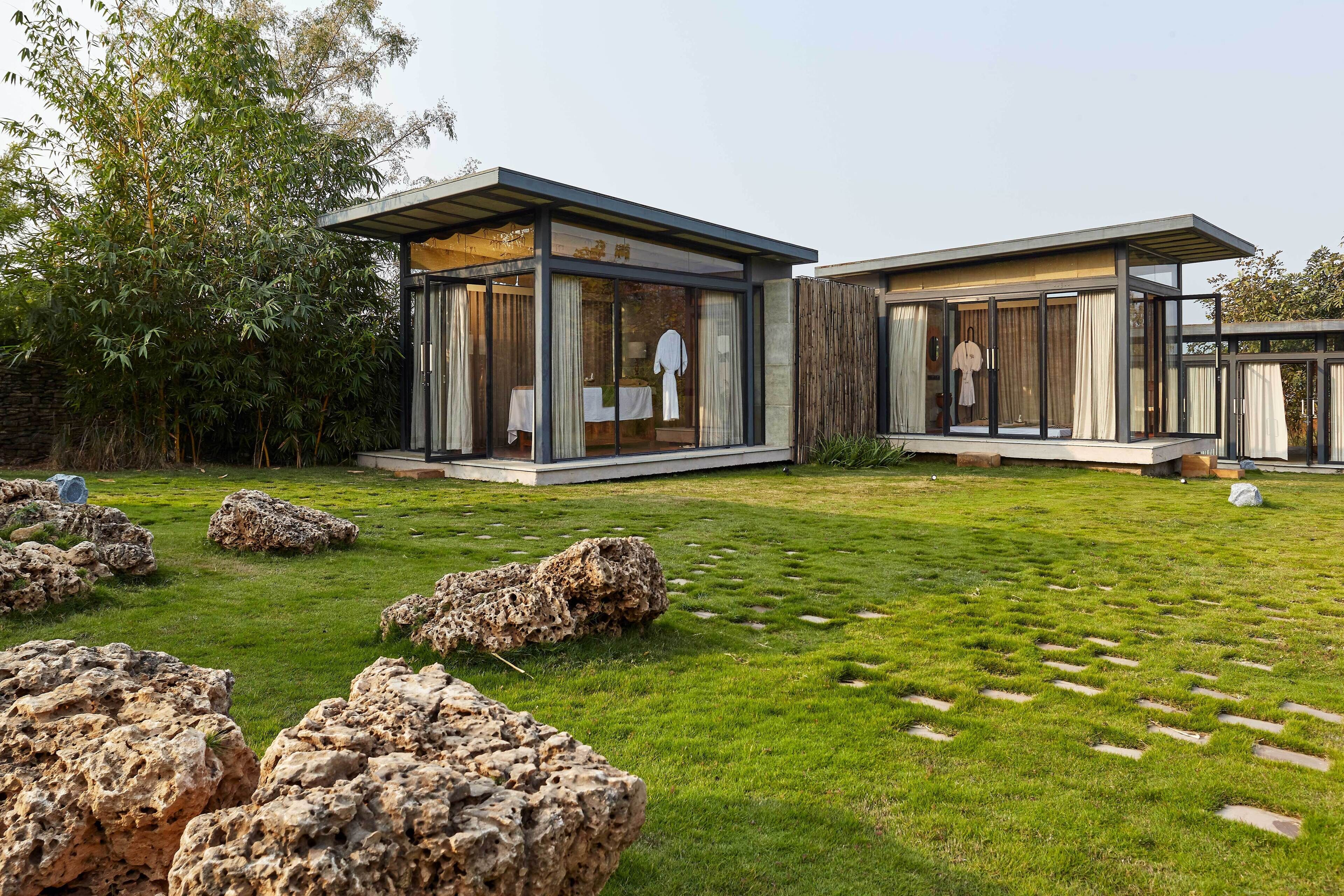 A modern house with glass walls and a well-maintained lawn.