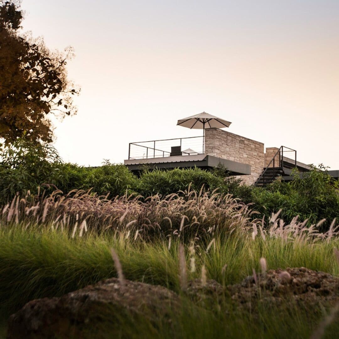 Un edificio moderno con fachada de piedra, techo plano y una escalera que lleva a un balcón.