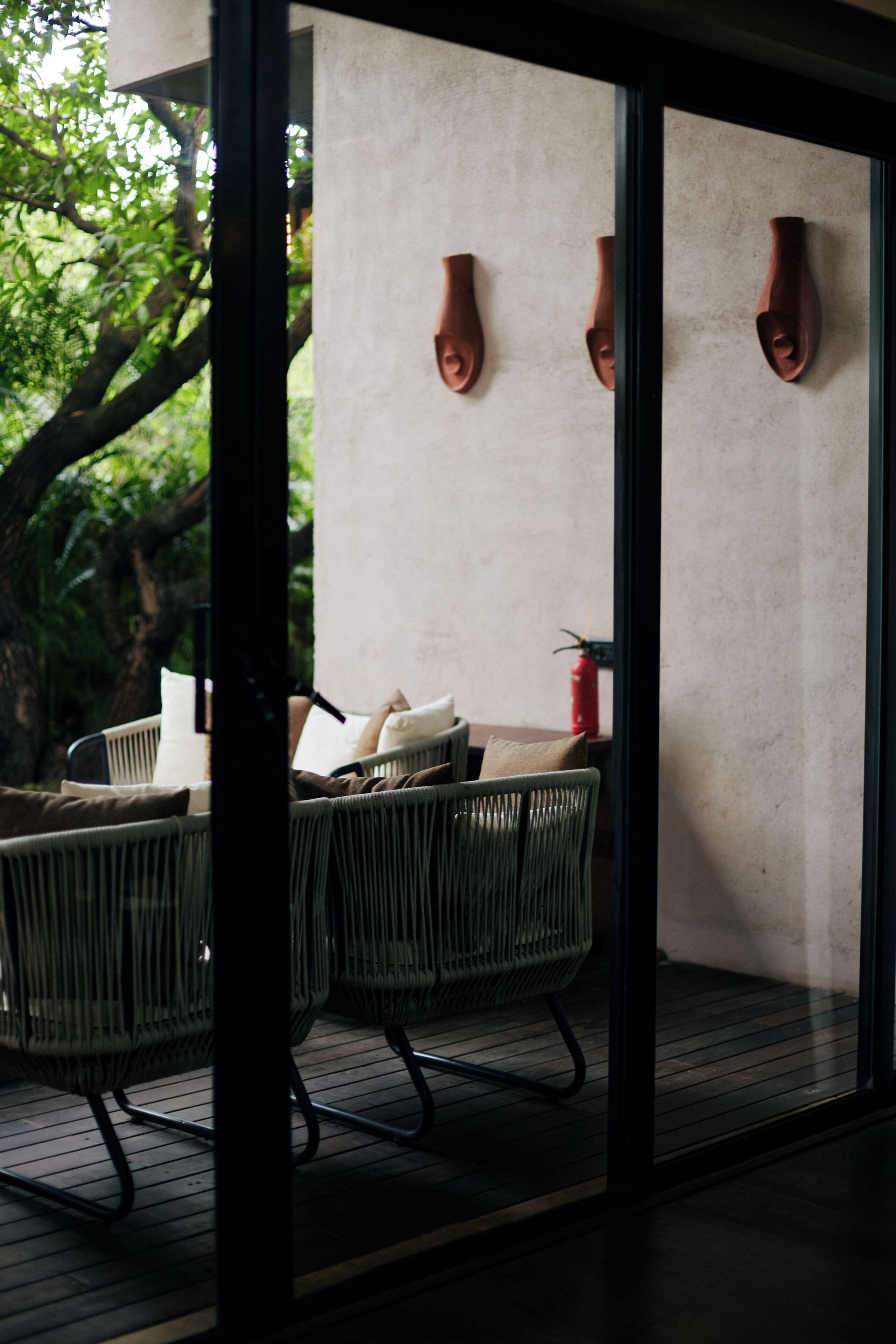 A modern interior with a glass partition, wicker furniture, and a fire extinguisher on the wall.