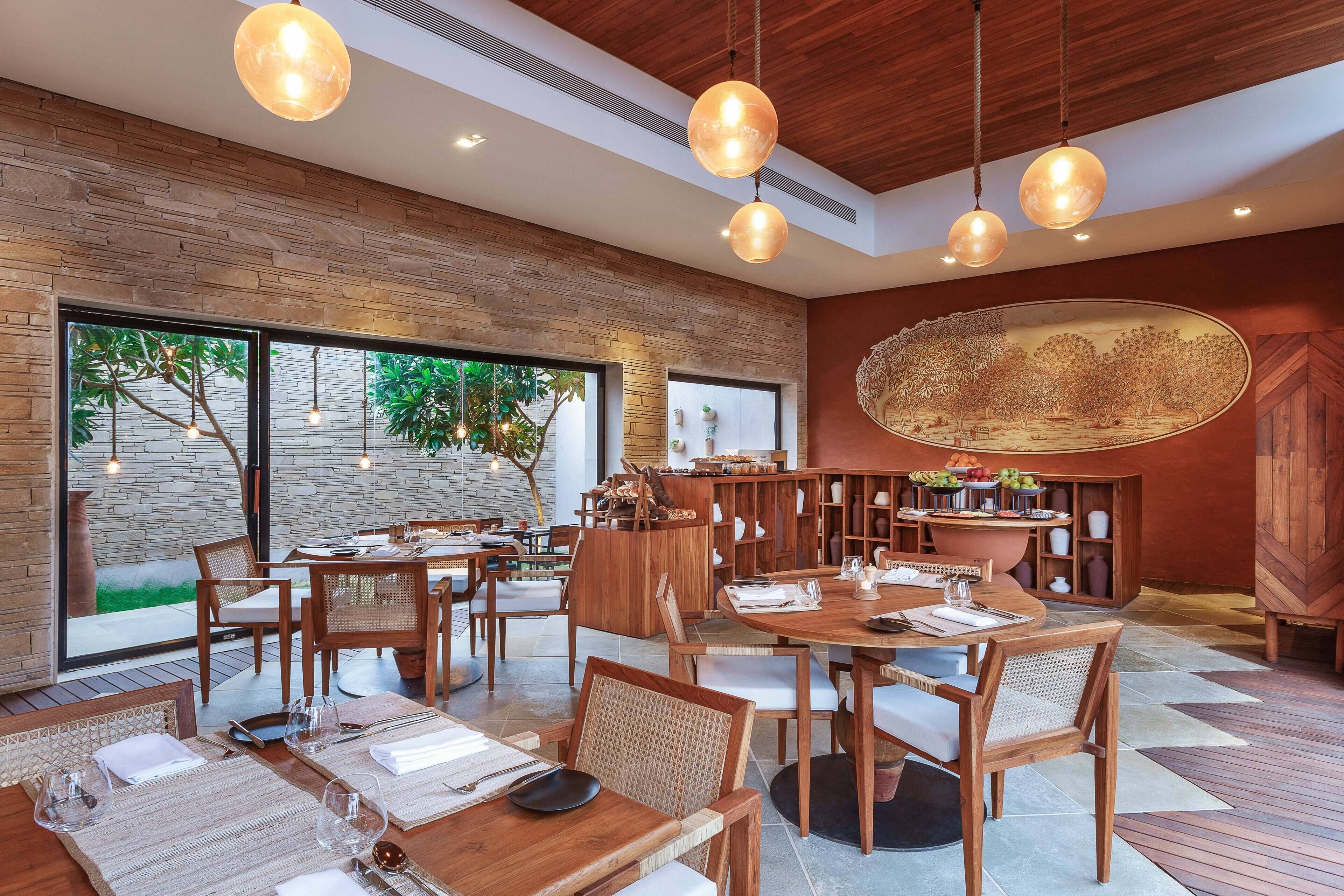 Un restaurante moderno con mobiliario de madera, ventanas amplias y lámparas colgantes.