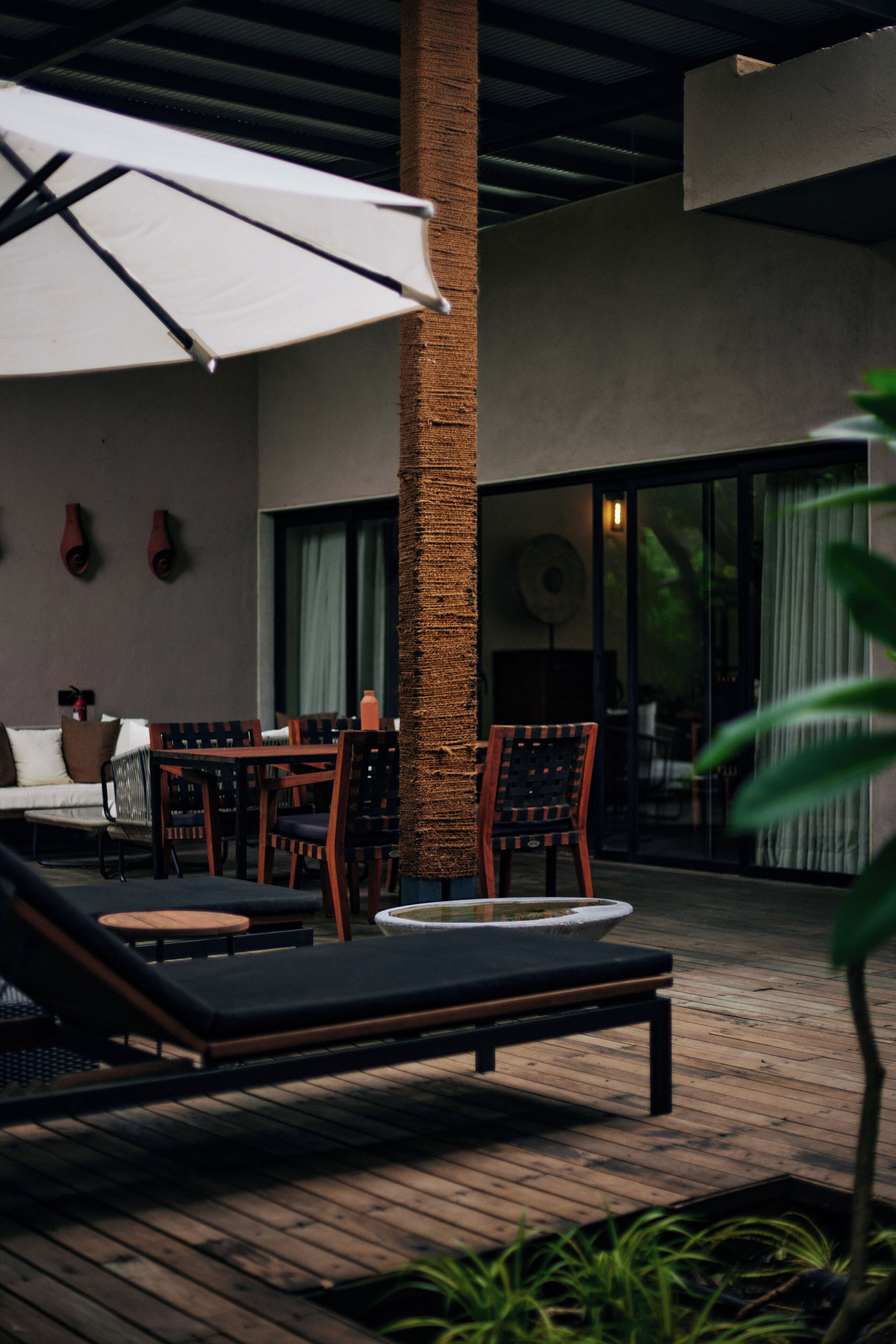 A modern outdoor seating area with lounge chairs, a table, and an umbrella.