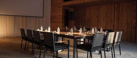 Une salle de conférence avec une longue table, des chaises noires et des bouteilles d’eau posées sur la table.