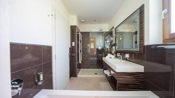 A modern bathroom with a large bathtub, a walk-in shower, and a vanity with a mirror.