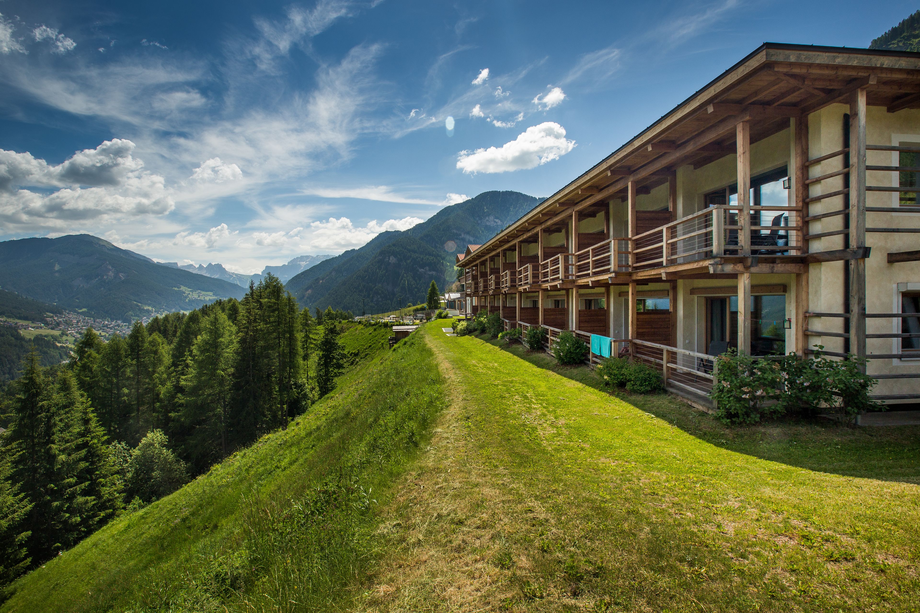 Ein Hotel mit Holzfassade, einem Balkon und Bergblick.