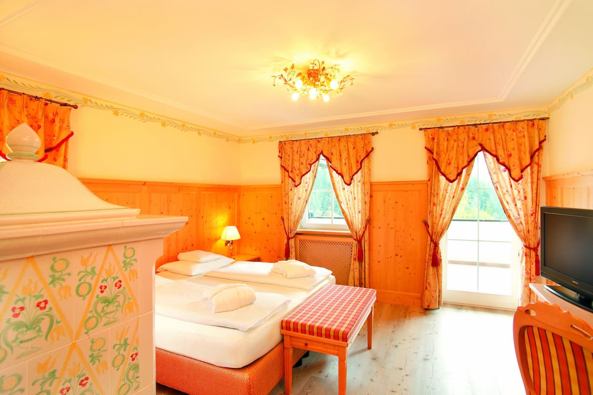 A hotel room with two beds, a television, and a window with curtains.