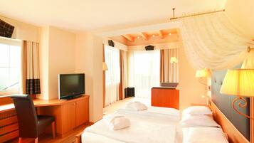 A hotel room with a bed, a desk with a television, a chair, and a window with curtains.