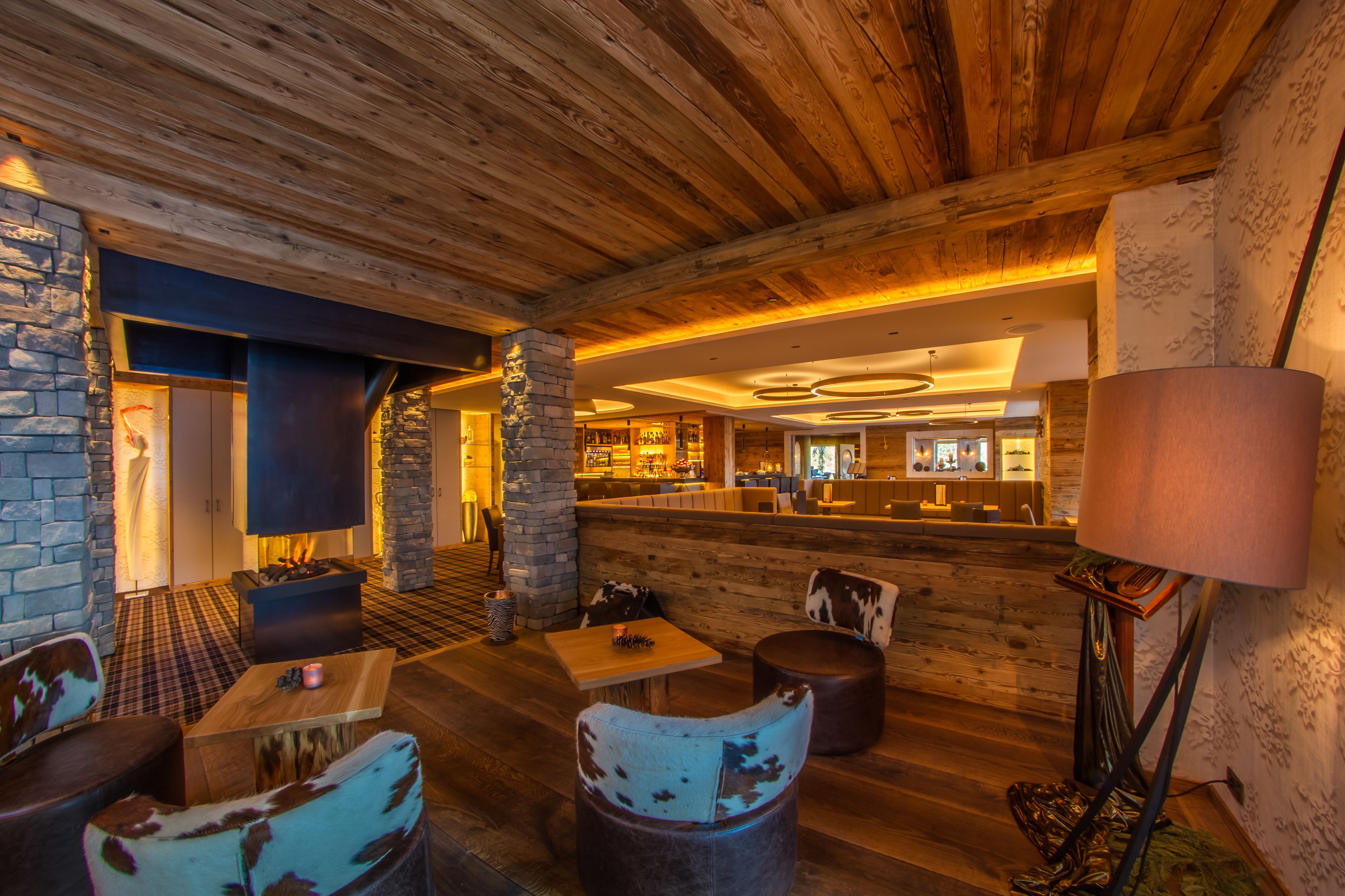 Un interior acogedor con vigas de madera, paredes de piedra, chimenea y una zona de bar.