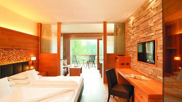 Een hotelkamer met een bed, een bureau, een televisie en een balkon met een tafel en stoelen.