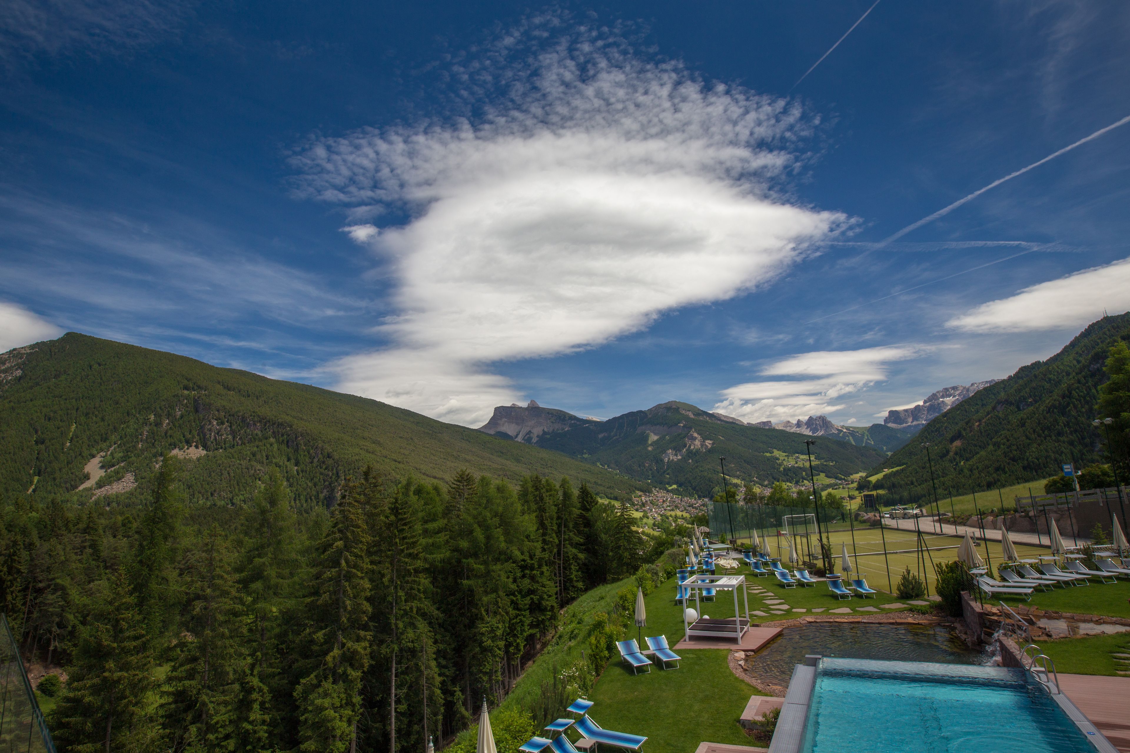 A pool area with lounge chairs and a view of a mountainous landscape.
