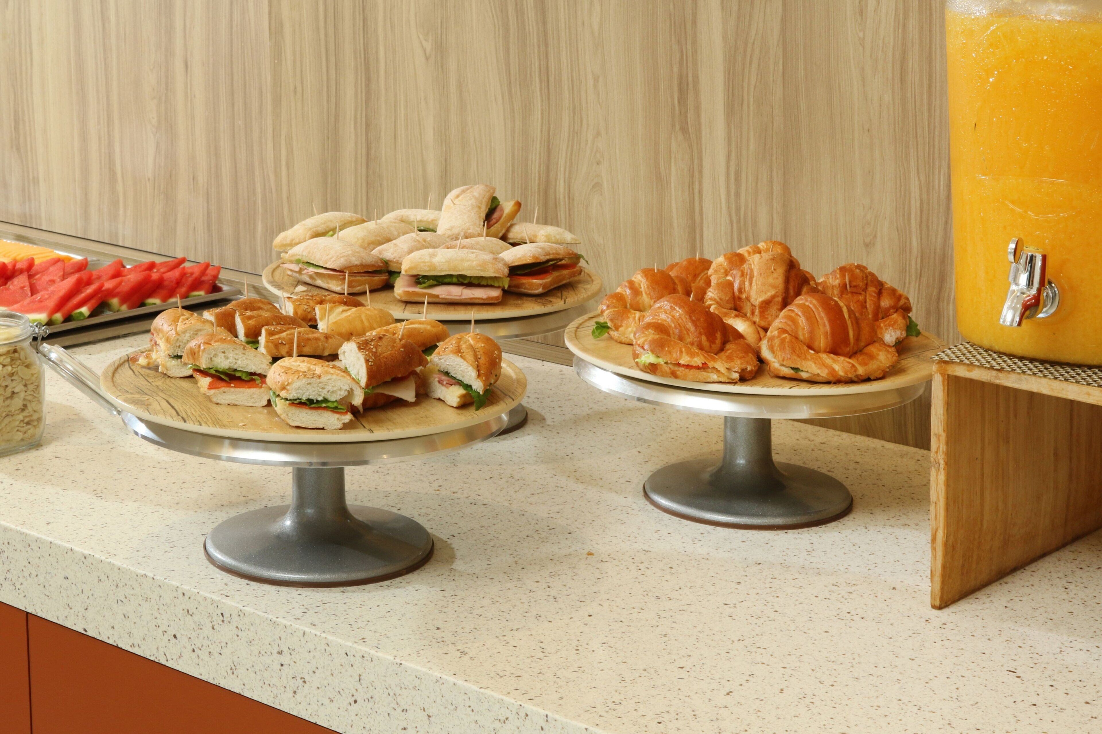 A buffet with various sandwiches, croissants, and a fruit platter.