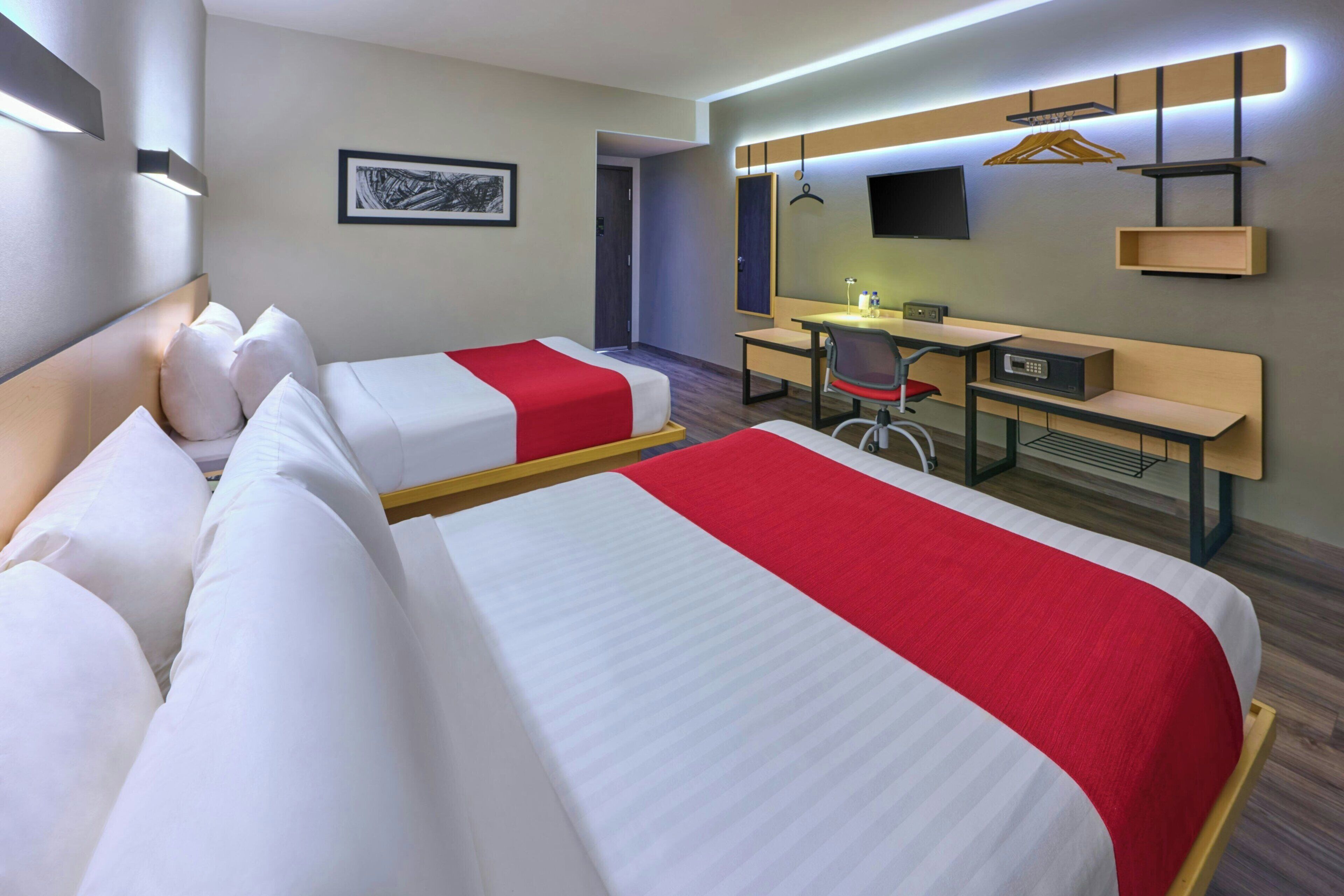 Een hotelkamer met twee bedden, een bureau, een stoel, een televisie en een wandplank.