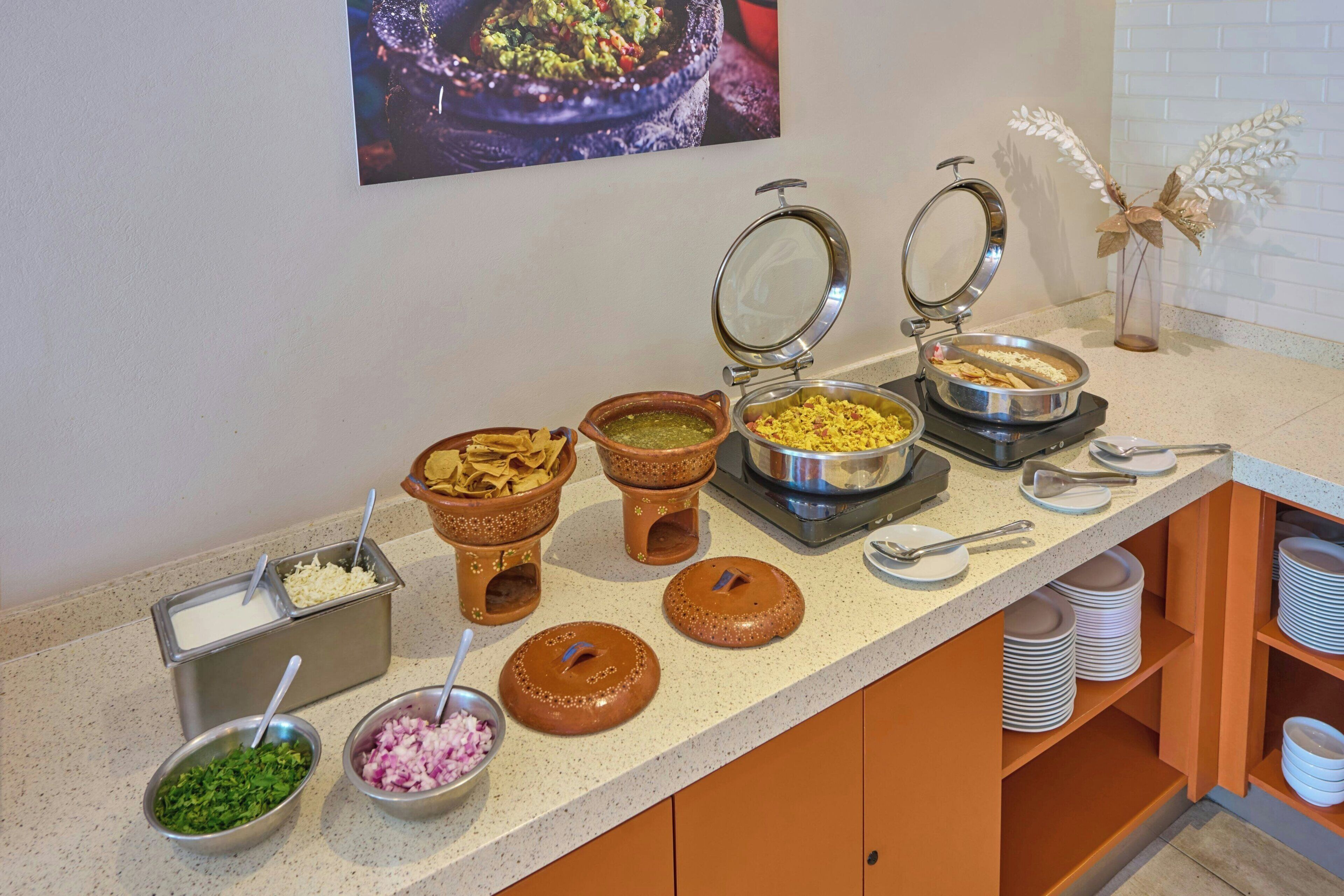 A buffet setup with various food containers and utensils.