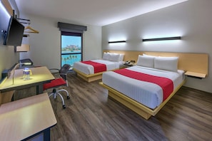 A hotel room with two beds, a desk, a chair, a TV, and a window with a view.