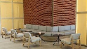 A modern lounge area with a curved seating arrangement, wooden chairs, and small round tables. - City Express Plus by Marriott Puerto Vallarta (Puerto Vallarta)