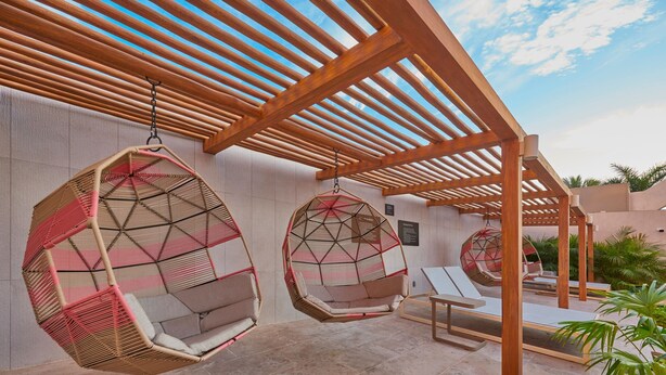 A covered outdoor seating area with hanging chairs and lounge chairs. - City Express Plus by Marriott Puerto Vallarta (Puerto Vallarta)