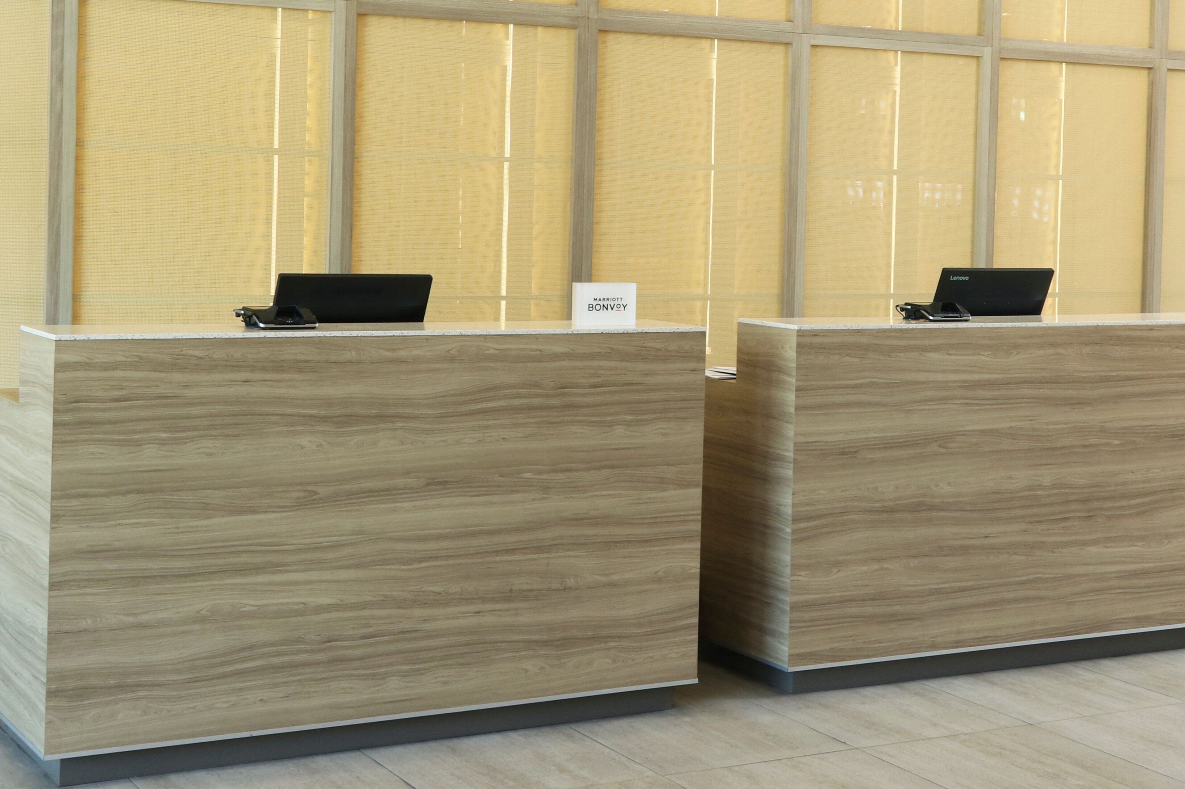 Two reception desks with laptops, a sign reading "MARTINI BONVOGNE," and a large window with blinds in the background.