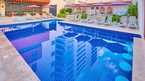 A swimming pool with tiled edges, lounge chairs, and umbrellas. - City Express Plus by Marriott Puerto Vallarta (Puerto Vallarta)