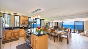 A modern kitchen with a large island, wooden cabinets, and a view of the ocean. - Premier Location, Huge Puu Poa Condo Ocean Views, Walk to 2 Beaches, Pool/Tennis (Princeville)