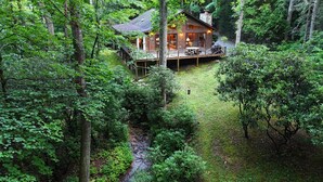 Een chalet omringd door dicht bos, met een terras en een zitgedeelte buiten.