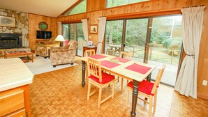 Een eetgedeelte met een houten tafel en stoelen, een open haard en uitzicht op de omgeving.