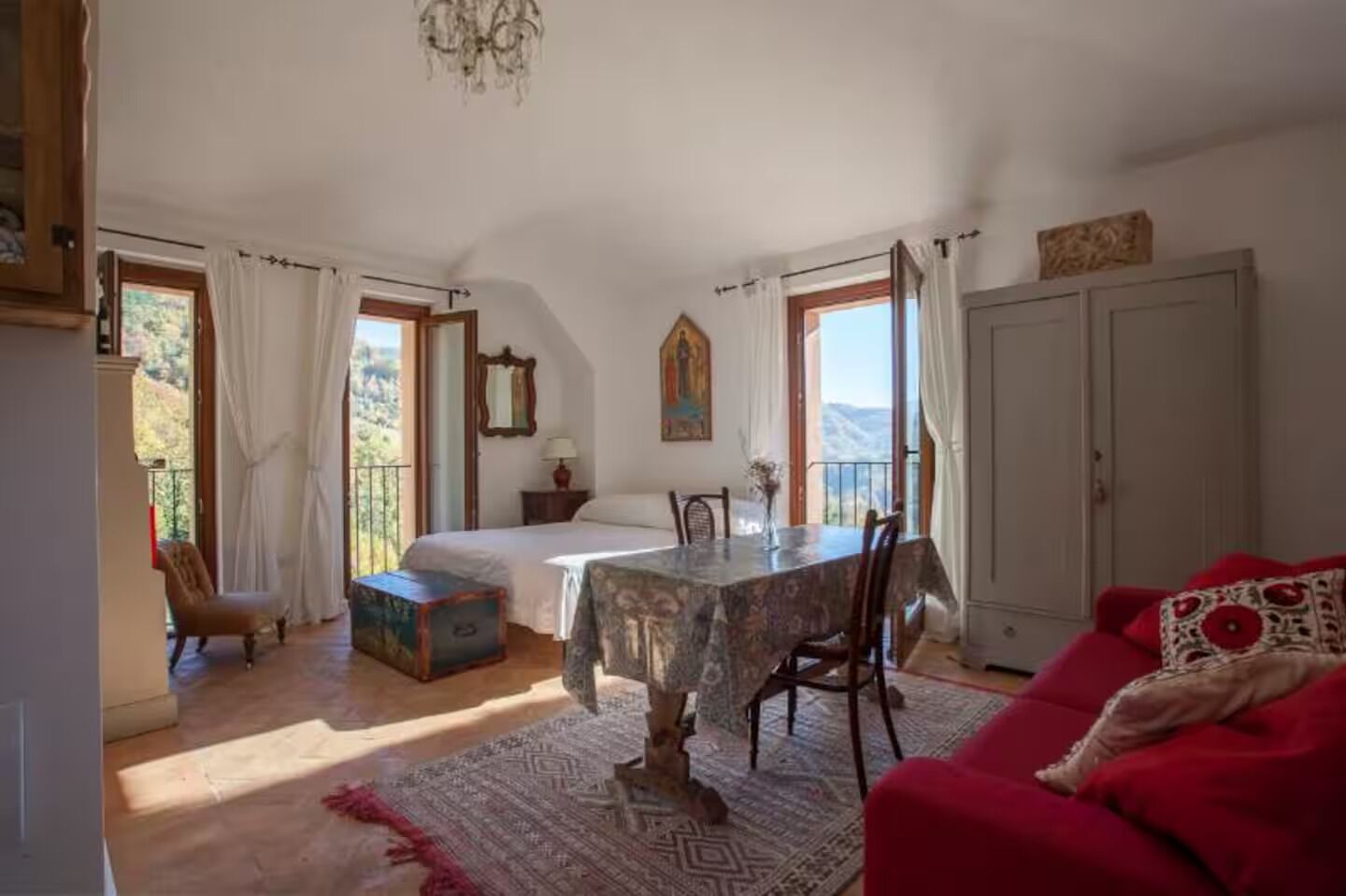 Un dormitorio con una cama, una mesa de comedor y un sofá rojo.