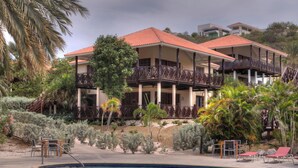 A resort with a pool, outdoor seating, and a building with balconies. - POCO POCO Villa - Caribbean Golf, Diving & Beach Holiday Home (Blue Bay Golf & Beach Resort, Willemstad, Curacao)