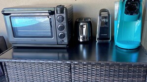 Une petite cuisine équipée d’un grille-pain, d’un four à micro-ondes et d’un mixeur, le tout posé sur un plan de travail noir.