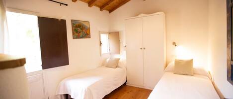 Un dormitorio con dos camas, un armario, una ventana y un cuadro en la pared.