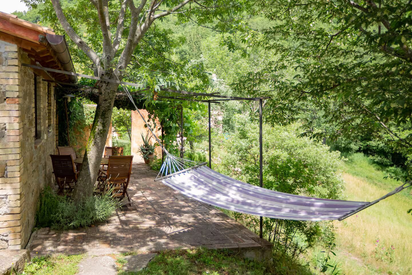 A hammock under a tree, a brick building, and a pathway.