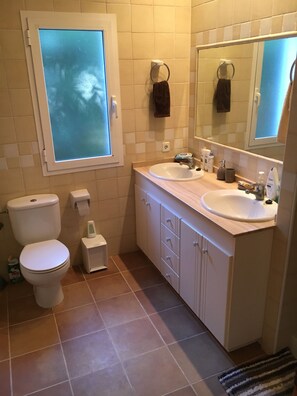 Un bagno con due lavandini, un water e una finestra.
