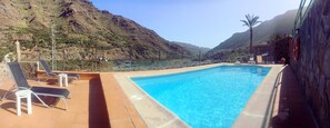 A swimming pool with lounge chairs and a stone wall.