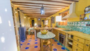 Une cuisine avec un sol carrelé, des meubles de cuisine en bois, une cuisinière et un luminaire suspendu.
