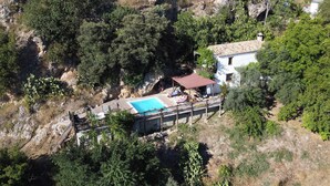 Vue aérienne d’une propriété dotée d’une piscine, d’un patio couvert et d’un bâtiment blanc avec un toit rouge.