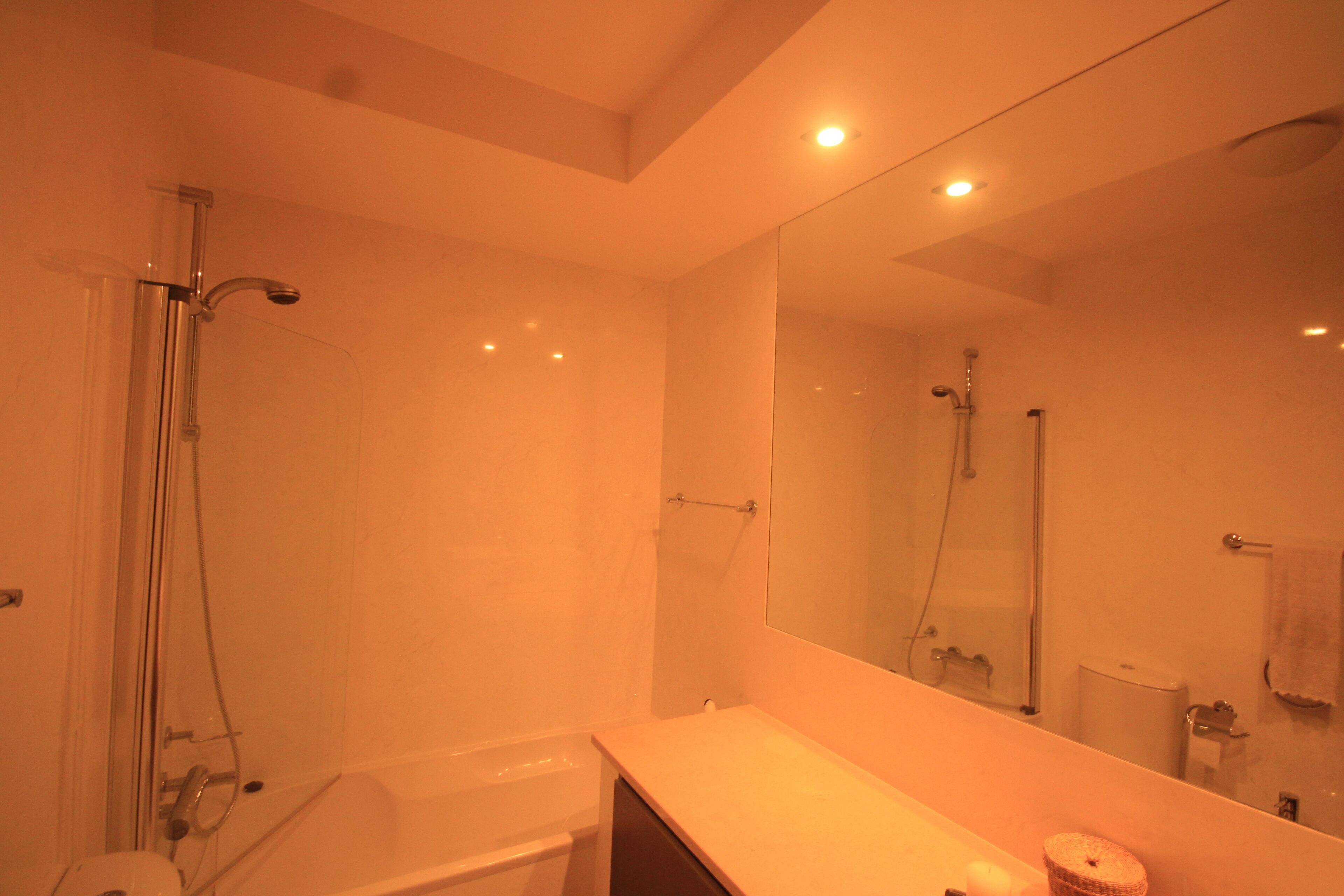 A modern bathroom with a bathtub, a shower, a large mirror, and a vanity with a sink.