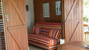 Una puerta de madera abierta que da a una habitación con un sofá de rayas coloridas, una mesa de madera y una silla azul.