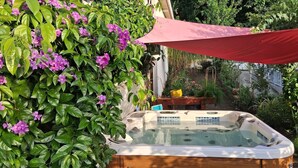 Un jacuzzi rodeado de follaje verde exuberante y flores moradas.