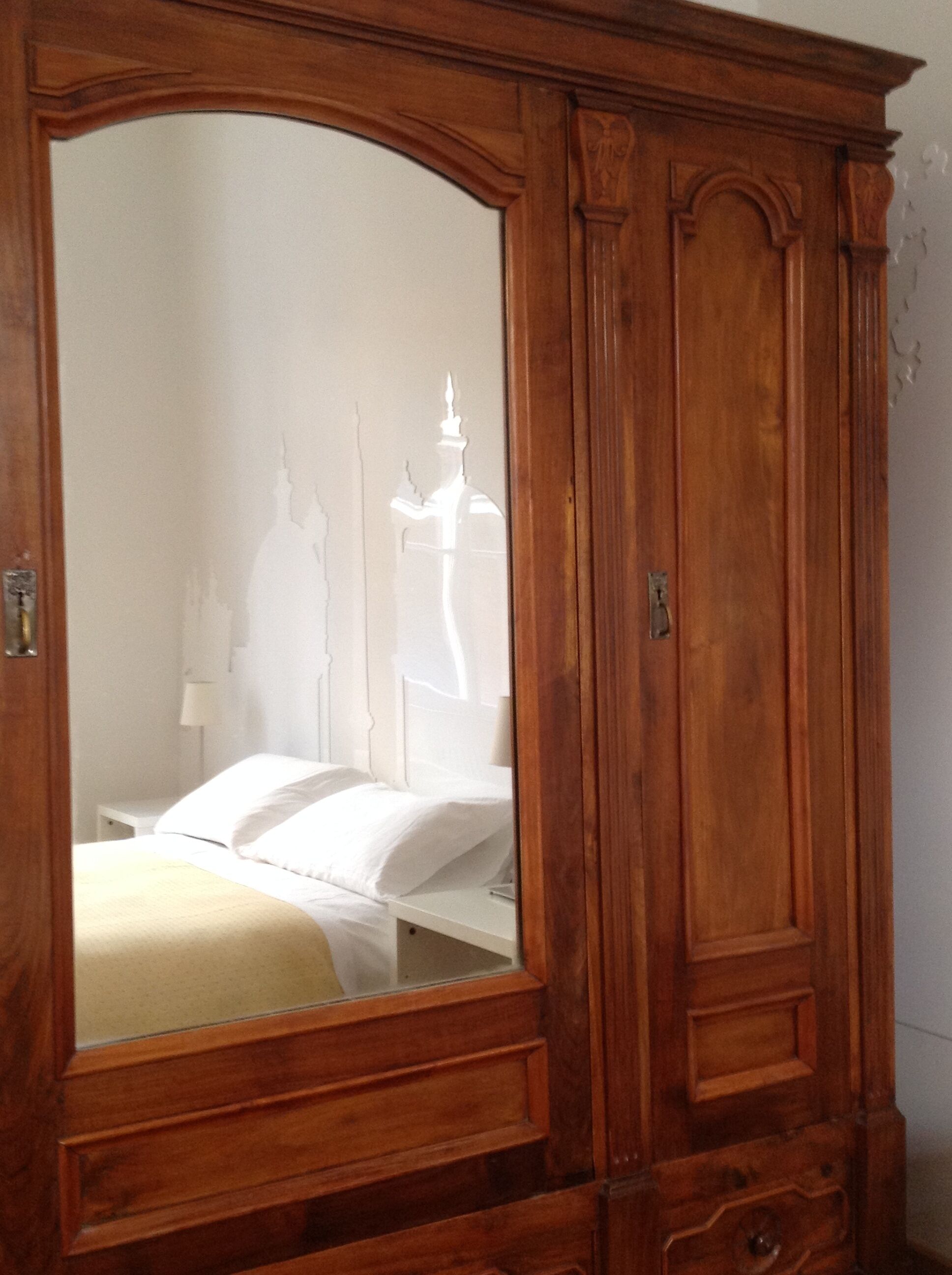 A wooden wardrobe with a large mirror.