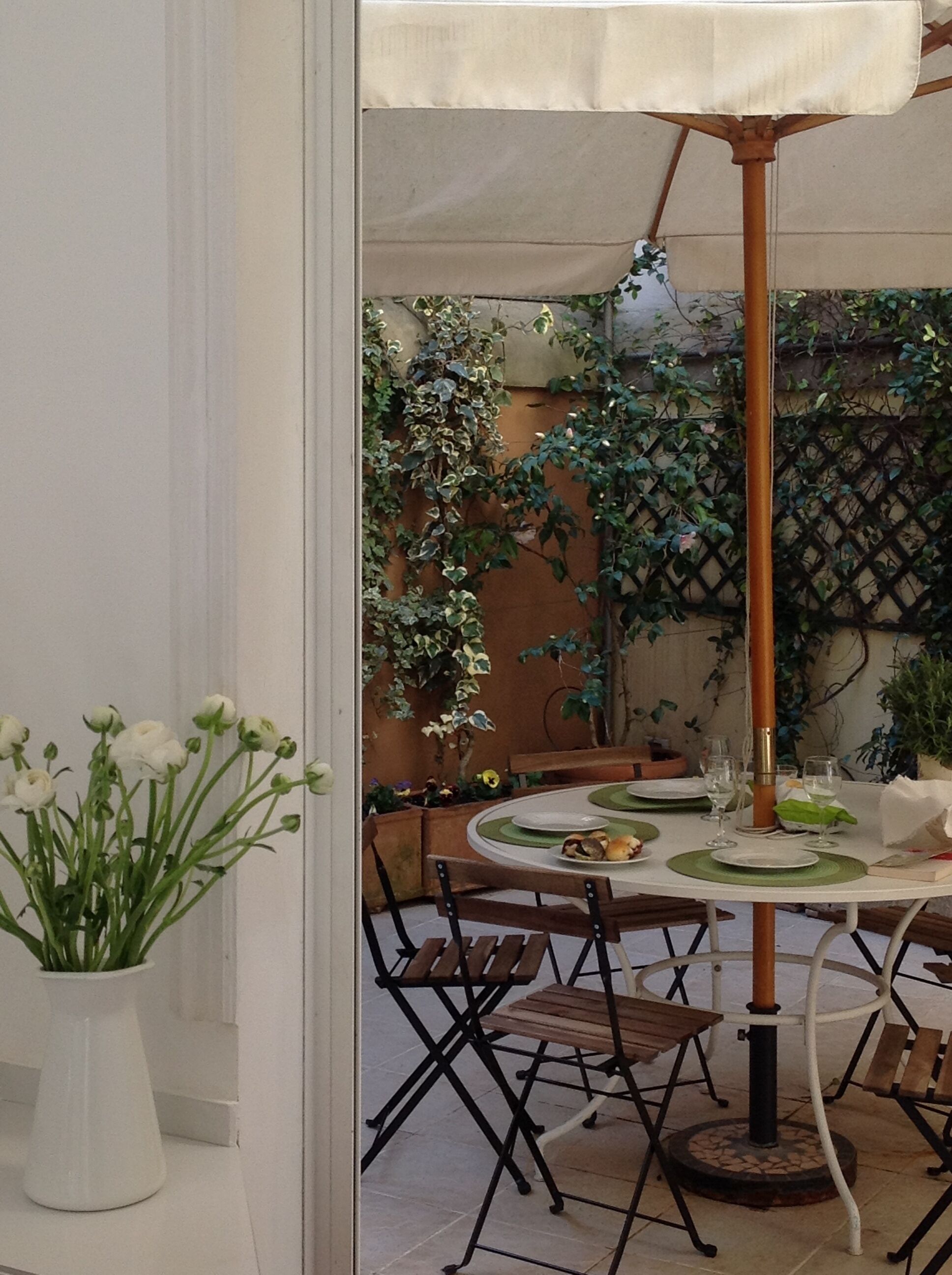 Un espace extérieur aménagé pour les repas, avec une table ronde, des chaises et un parasol.