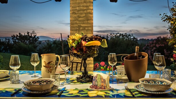 Ein Tisch ist für eine Mahlzeit gedeckt, mit Blick auf die Landschaft im Abenddämmerung.