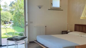 A bedroom with a bed, a chair, a window, and a radiator.