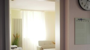 Una sala de estar moderna con un sofá blanco, una mesita y un reloj en la pared.