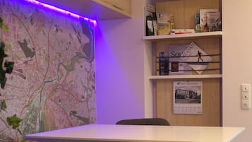 Une pièce avec une carte accrochée au mur, une table, des chaises et des étagères remplies de livres et une affiche.