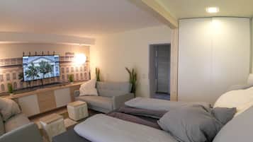 Un appartement moderne comprenant un canapé, deux lits, une télévision et donnant sur un immeuble.