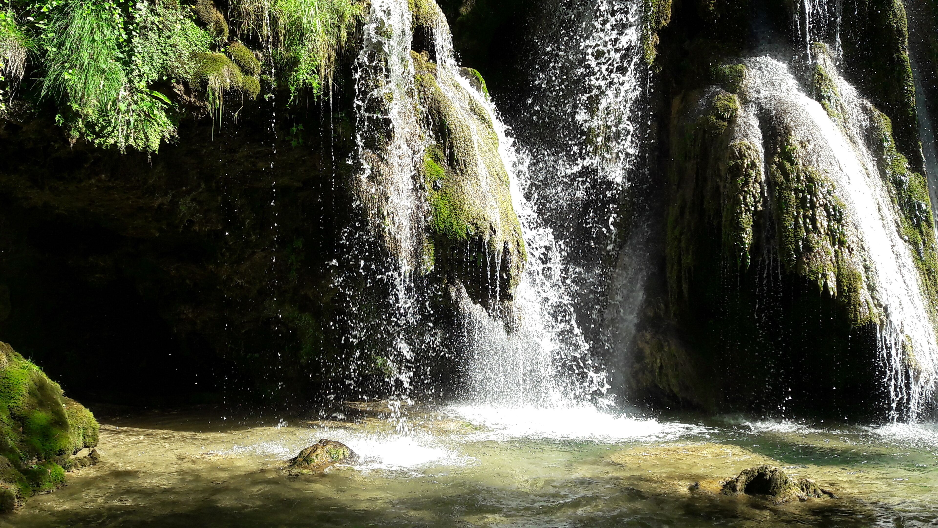 Een waterval die over mosbedekte rotsen stroomt.