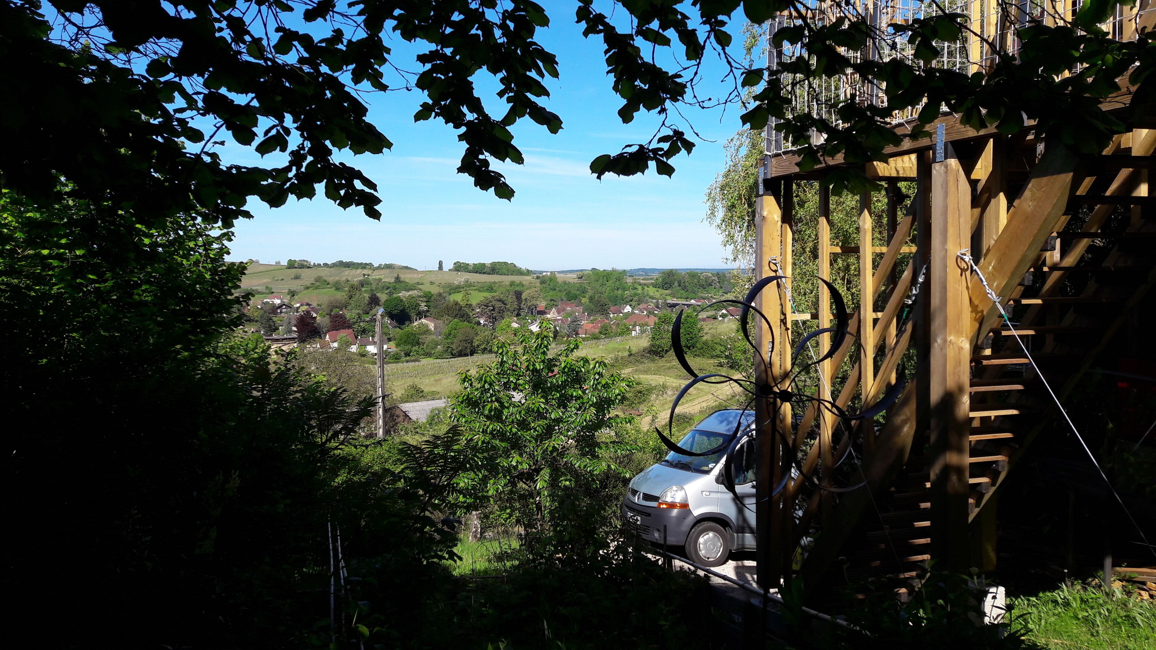 A view of a residential area with houses, a car, and a wooden structure with cables.