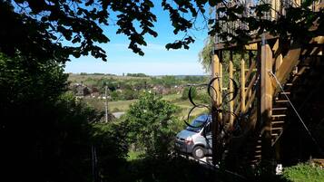 A view of a residential area with houses, a car, and a wooden structure with cables.
