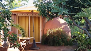 A patio area with a table and chairs, a large umbrella, and a potted plant.
