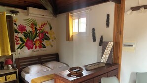 Een slaapkamer met een bed, nachtkastje, lamp en een wand met een bloemschilderij.